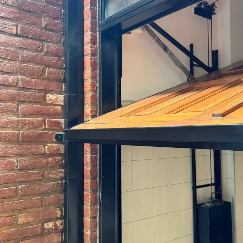Cambio de zócalo y mantenimiento integral en portón levadizo. Recambio del zócalo deteriorado en un portón levadizo con marco contenedor de hierro. Originalmente un portón pivotante de tres hojas de madera, fue adaptado a levadizo. Se realizó un servicio integral de motorización y revisión de lingas y contrapesos. Trabajo realizado por HERREELEC.